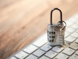 Nahaufnahme von Vorhängeschloss und Schlüsseln auf einer Computertastatur als Symbol für IT-Sicherheit und Datenschutz