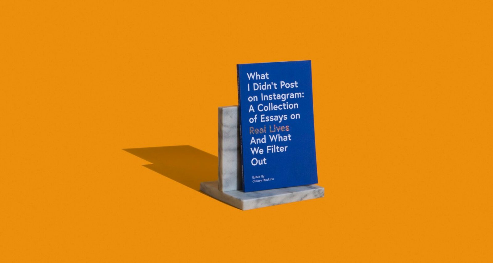 Das Buch „What I didn't post on Instagram“ steht auf grauen Marmorbuchstützen, fotografiert aus der Nähe auf glatter Oberfläche.