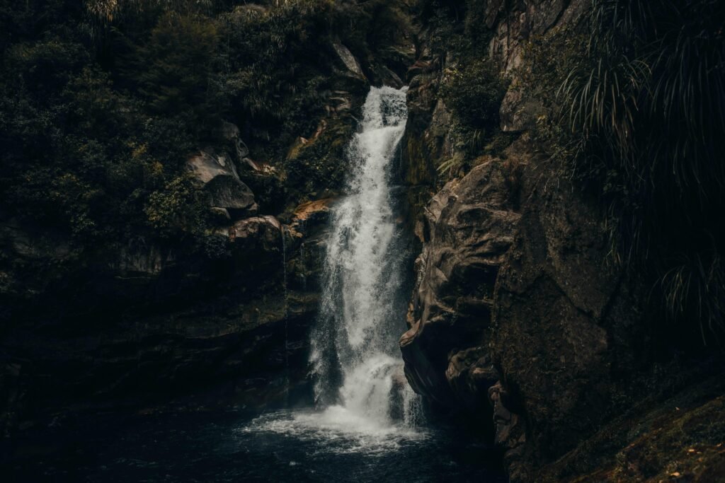 Mehrere Wasserfälle fließen bei Tageslicht durch eine braune, felsige Berglandschaft mit steinigem Untergrund