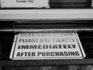 Ein weiß-schwarzes Straßenschild zeigt klare Richtungshinweise im urbanen Straßenverkehr.