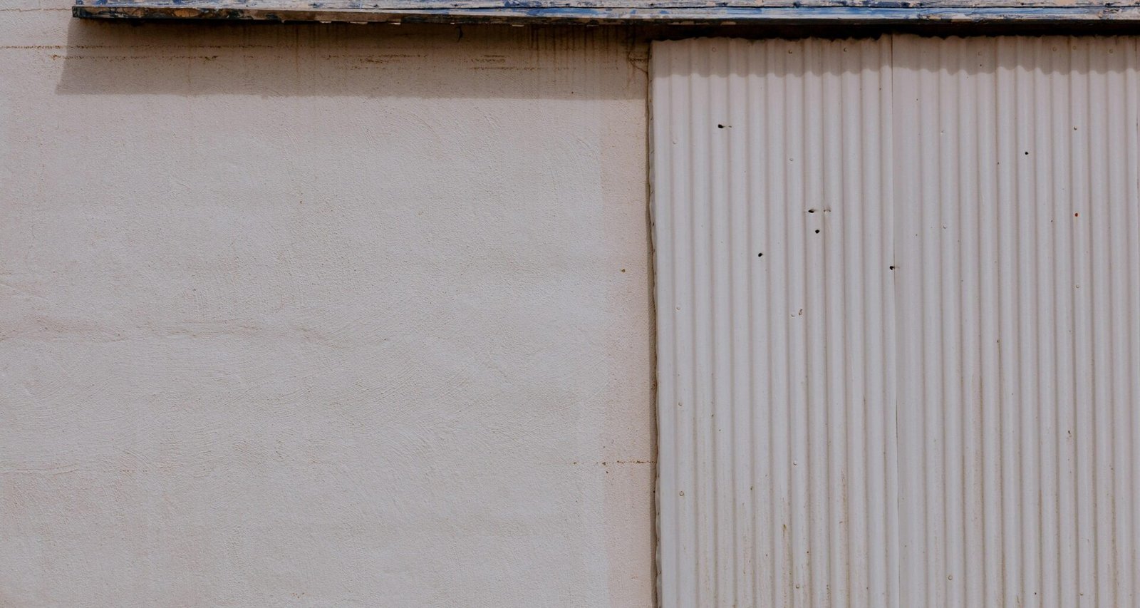 Weiße Holzwand mit schlichter weißer Holztür als Beispiel für minimalistisches Raumdesign und moderne Einrichtung.