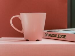 Weiße Keramiktasse auf weißem Tisch, neutral fotografiert aus der Vogelperspektive als Symbol für Minimalismus