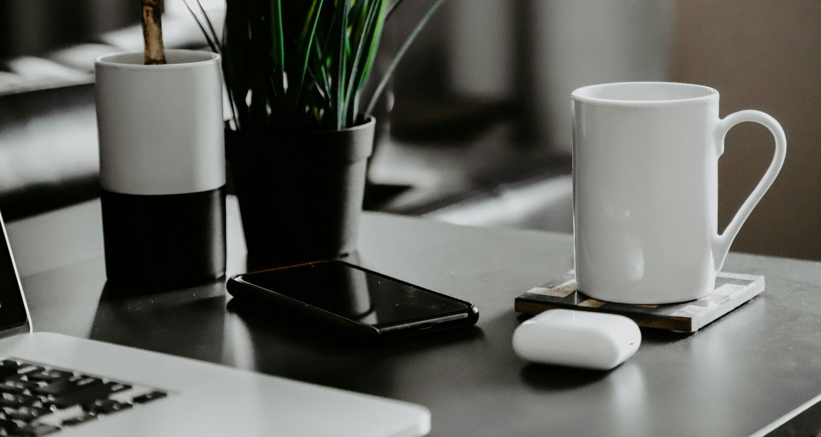 Weiße Keramiktasse steht auf einem weißen Tisch vor neutralem Hintergrund, minimalistisches und modernes Wohnaccessoire