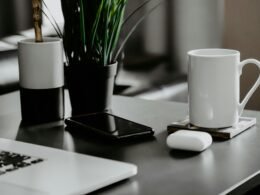 Weiße Keramiktasse steht auf einem weißen Tisch vor neutralem Hintergrund, minimalistisches und modernes Wohnaccessoire