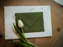 Weiße Tulpen liegen auf einem grünen Umschlag, arrangiert als dekoratives Stillleben für saisonale Dekoideen.