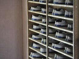 Ein Regal mit weißen und blauen Schuhen steht in einem hellen Zimmer. Die Schuhe sind ordentlich nebeneinander aufgereiht.