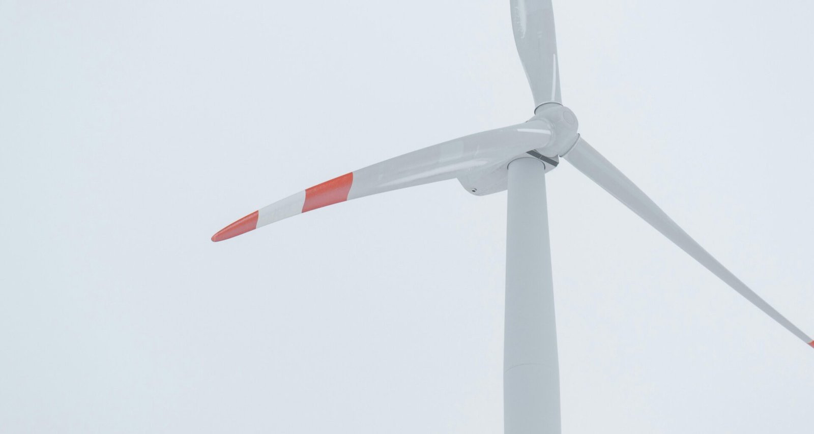 Weiße Windkraftanlage mit roten Elementen zur Stromerzeugung bei Tag, Symbol für erneuerbare Energien und Technologie