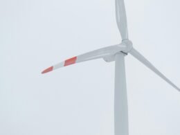 Weiße Windkraftanlage mit roten Elementen zur Stromerzeugung bei Tag, Symbol für erneuerbare Energien und Technologie