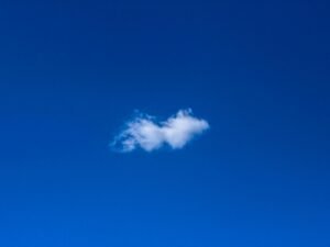 Weiße Wolke am blauen Himmel, minimalistische Darstellung der Natur und Weite des Himmels ohne weitere Elemente.