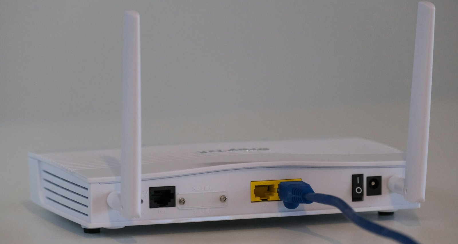 Weißer WLAN-Router auf einem weißen Tisch, minimalistisches Design, geeignet für moderne Heim- oder Büronetzwerke.