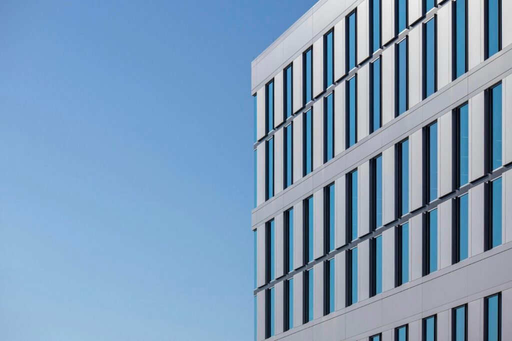 Weißes Betongebäude mit minimalistischer Fassade vor klarem blauen Himmel bei Tageslicht