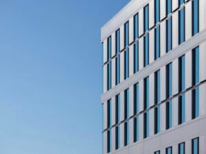 Weißes Betongebäude mit minimalistischer Fassade vor klarem blauen Himmel bei Tageslicht