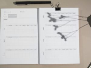 Weiße Druckerblätter liegen auf einem braunen Holztisch, passend für Büro- und Arbeitsumgebungen abgebildet