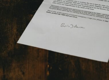 Weiße Druckerpapierblätter auf einem braunen Holztisch, arrangiert in einer typischen Büroumgebung, Aufnahme von Annie Spratt