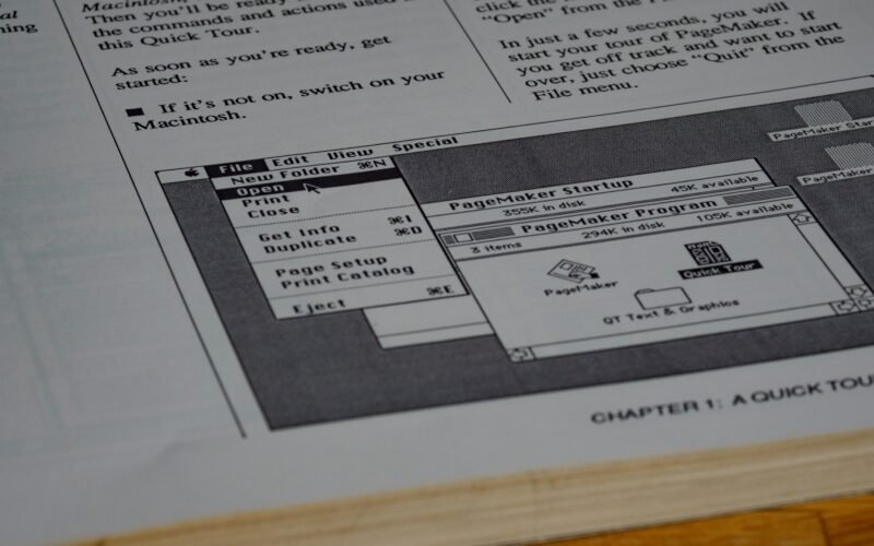 Mehrere weiße Druckerpapierblätter liegen ordentlich auf einem braunen Holztisch in einer modernen Büroumgebung.