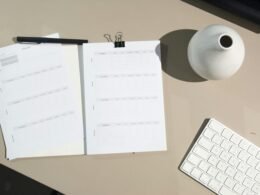 Gestapelte weiße Druckerpapiere liegen auf einem braunen Holztisch und bieten eine schlichte Arbeitsatmosphäre.