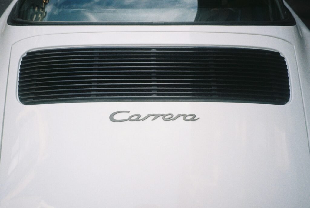 Rückansicht eines weißen Autos mit dem Schriftzug Carrera am Heck, Detailperspektive auf Fahrzeugemblem