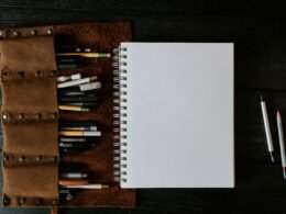 Weißes Spiralnotizbuch liegt geöffnet auf einem braunen Holztisch, ideal für Notizen oder kreative Planung.