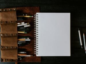 Weißes Spiralnotizbuch liegt geöffnet auf einem braunen Holztisch, ideal für Notizen oder kreative Planung.