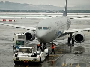 Weißes und blaues Flugzeug steht am Flughafen bei Tageslicht auf dem Rollfeld, bereit für den nächsten Flug.
