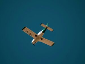 Weißes und braunes Flugzeug fliegt tagsüber unter blauem Himmel, aufgenommen von Grianghraf.