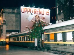 Leuchtende Billboard-Werbung an Zugschienen bei Nacht, vorbeifahrende Züge und beleuchtete Werbetafeln in urbaner Umgebung