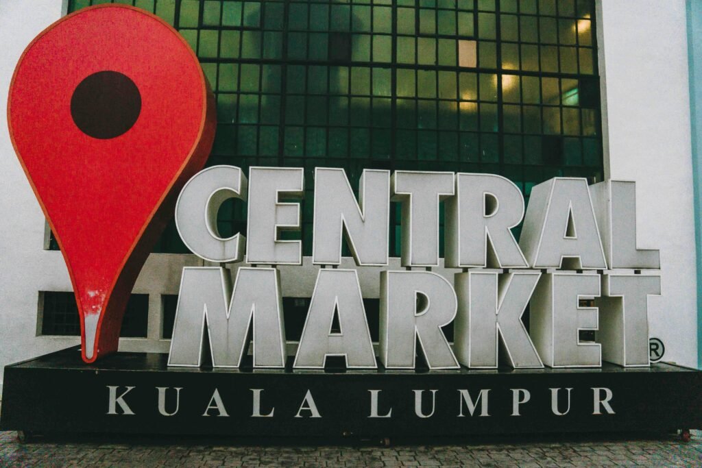 Haupteingang und Außenbereich des Zentralmarkts in Kuala Lumpur mit Menschen und Marktständen.