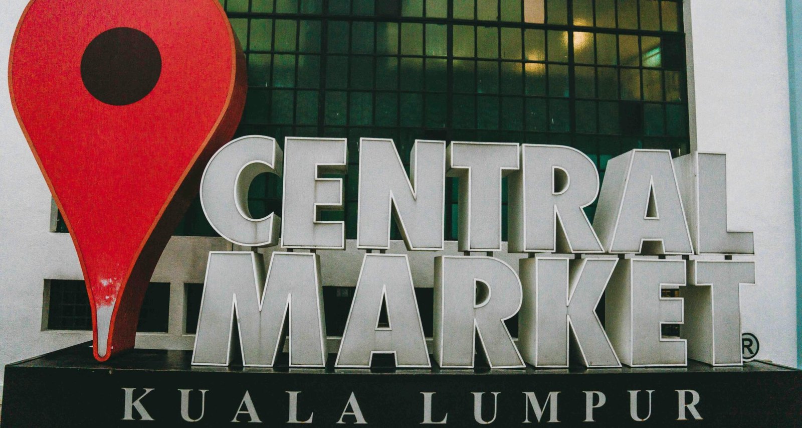 Haupteingang und Außenbereich des Zentralmarkts in Kuala Lumpur mit Menschen und Marktständen.