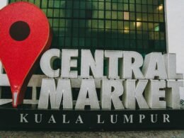 Haupteingang und Außenbereich des Zentralmarkts in Kuala Lumpur mit Menschen und Marktständen.