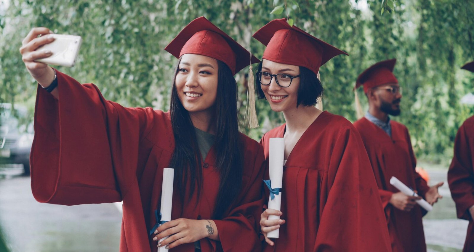 Zwei frischgebackene Absolventen im Talar machen gemeinsam ein Selfie nach ihrer Abschlussfeier