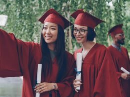 Zwei frischgebackene Absolventen im Talar machen gemeinsam ein Selfie nach ihrer Abschlussfeier