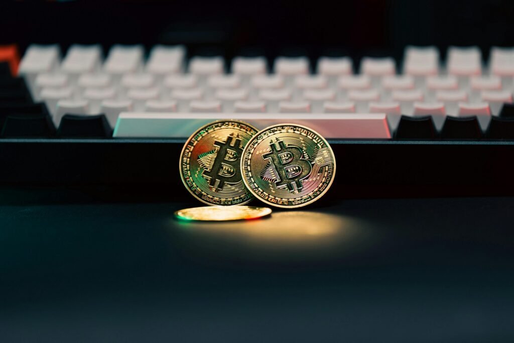 Zwei Bitcoins befinden sich neben einer schwarzen Computertastatur und stehen für digitales Geld und Technologie.