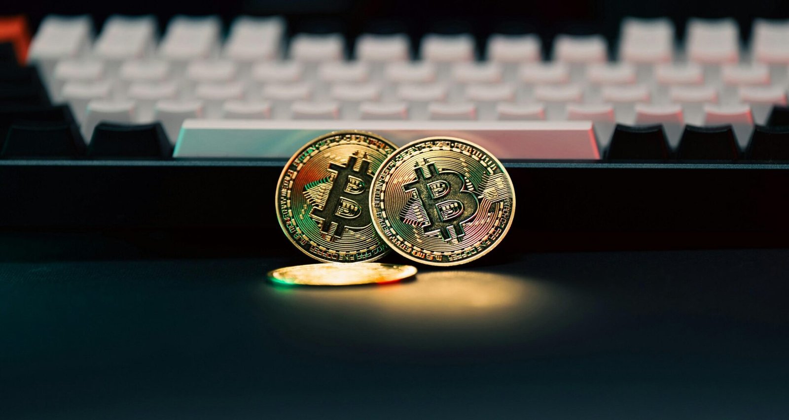 Zwei physische Bitcoin-Münzen liegen neben einer Computer-Tastatur auf einem Schreibtisch.