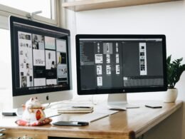 Zwei Computer-Monitore nebeneinander auf einem Holzschreibtisch für modernes Arbeiten im Büro oder Homeoffice