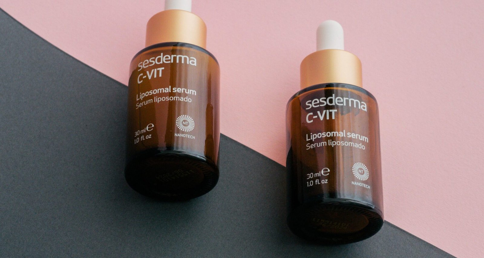 Zwei Flaschen Gerania Vitamin C auf einem geteilten rosa und schwarzen Untergrund, nebeneinander platziert