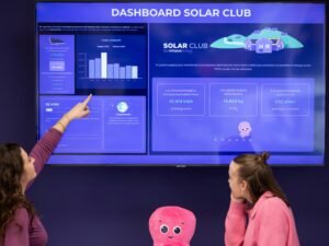Zwei Frauen betrachten gemeinsam die Anzeige eines Solar-Dashboards in einem modernen Innenraum.