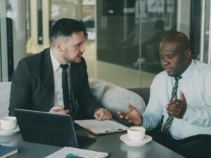 Zwei Geschäftsmänner sitzen an einem Tisch und prüfen Unterlagen während einer Besprechung in einem modernen Büro.