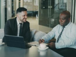Zwei Geschäftsleute sitzen in einem Café und besprechen gemeinsam Dokumente bei einer Tasse Kaffee.
