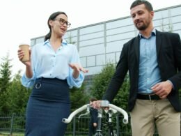 Zwei Business-Profis unterhalten sich im Freien neben einem Fahrrad, Fokus auf urbane Arbeitsumgebung