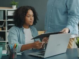 Zwei Kollegen analysieren Dokumente am Büroschreibtisch und besprechen gemeinsam die nächsten Schritte