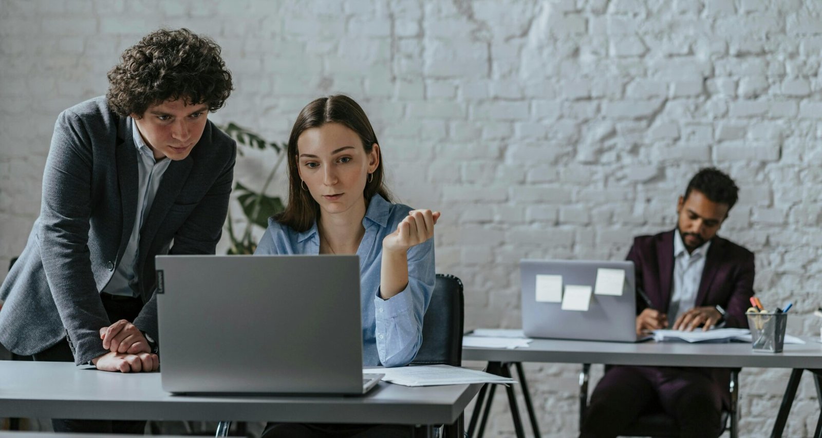 Zwei Kollegen sitzen an einem Schreibtisch und arbeiten zusammen an einem Laptop in einem modernen Büro