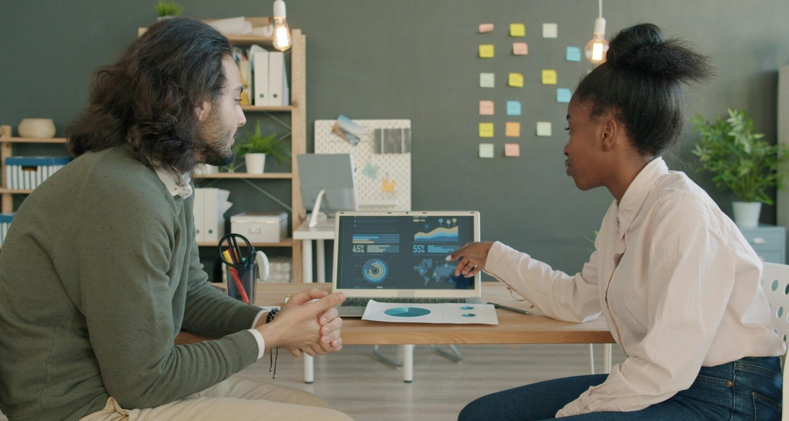 Zwei Kollegen sitzen zusammen und analysieren gemeinsam Geschäftsdaten auf einem Laptop am Arbeitsplatz.