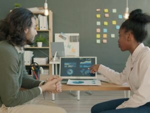 Zwei Kollegen sitzen zusammen und analysieren gemeinsam Geschäftsdaten auf einem Laptop am Arbeitsplatz.