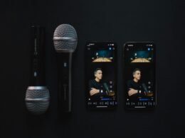 Zwei moderne Mikrofone und zwei Smartphones, die eine Podcast-Aufnahme auf einem Studio-Tisch zeigen