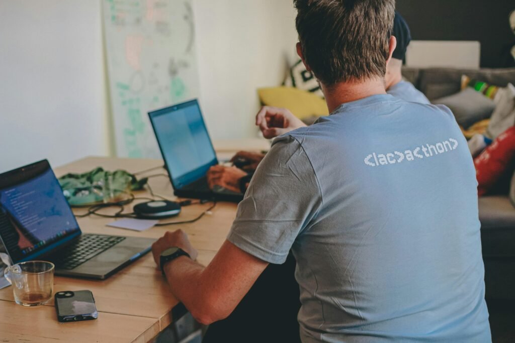 Zwei Menschen sitzen zusammen an einem Tisch und arbeiten jeweils an ihren Laptops im Büroalltag.