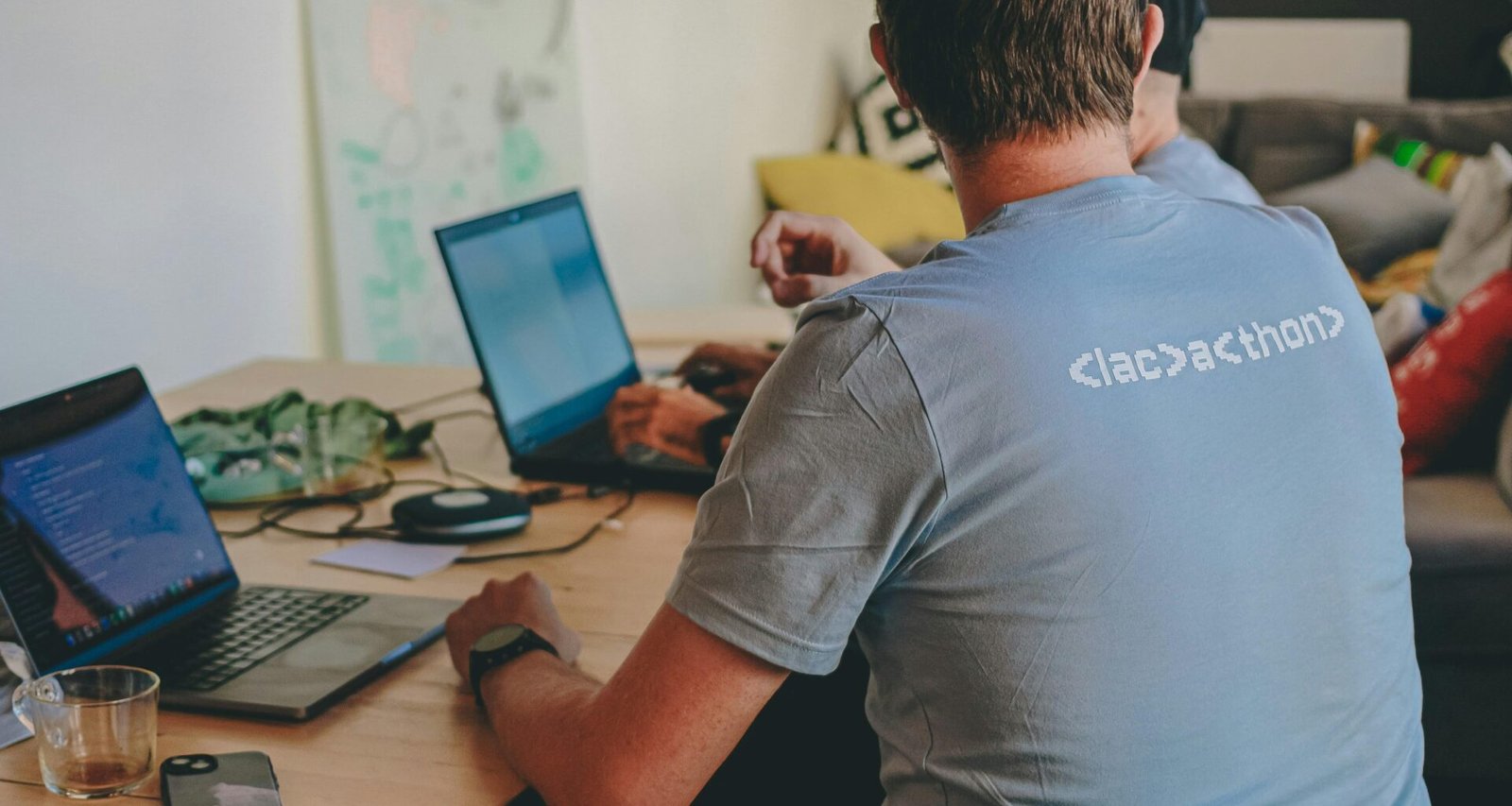 Zwei Personen sitzen an einem Tisch und arbeiten jeweils an einem Laptop in einer modernen Arbeitsumgebung