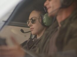 Blick ins Cockpit eines Helikopters mit zwei Personen, die Headsets tragen und die Instrumente bedienen