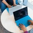 Zwei Personen sitzen gemeinsam am Schreibtisch und verwenden ein Microsoft Surface Tablet bei der Arbeit