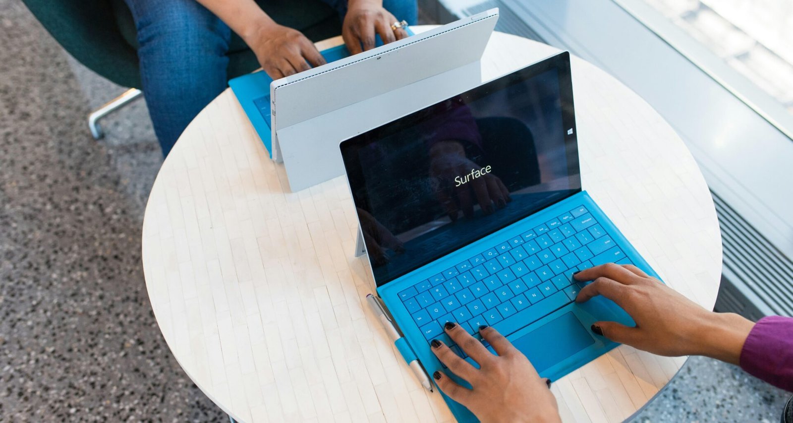 Zwei Personen sitzen gemeinsam am Schreibtisch und verwenden ein Microsoft Surface Tablet bei der Arbeit