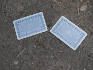 Zwei Spielkarten liegen nebeneinander auf einer rauen Oberfläche und verdeutlichen Glücksspiel und Strategie.